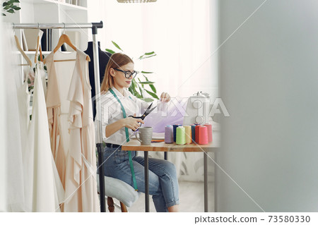 Woman sitting in studio and sew cloth Woman sitting in studio and sew cloth 73580330