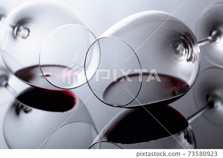 Glasses of red wine on a black reflective background. 73580923