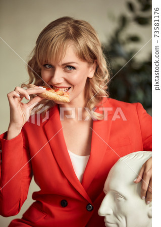 casual woman at home smiling and eating pizza 73581176