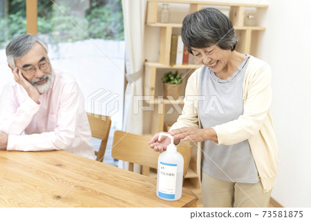 Senior woman doing alcohol disinfection Senior woman doing alcohol disinfection 73581875
