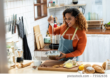 African American woman looking streaming live video while cooking at home African American woman looking streaming live video while cooking at home 73582636