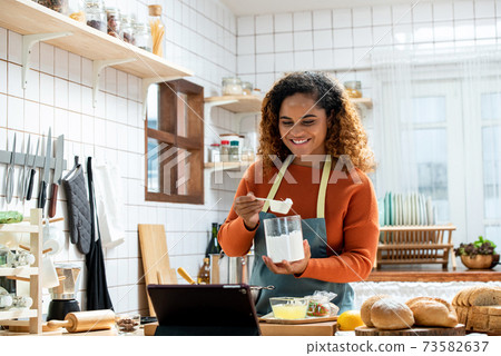 African American woman learning online cooking via tablet in kitchen at home 73582637