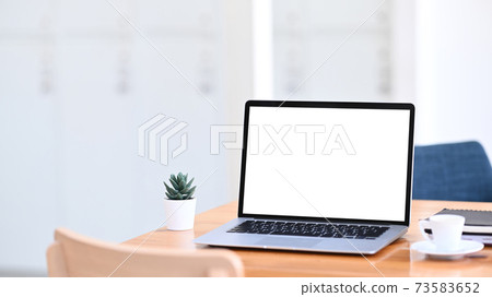 Minimal workplace with mock up laptop computer with white screen on wooden table. 73583652