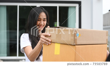 Young Asian woman customer receiving package from delivery man at home. 73583789