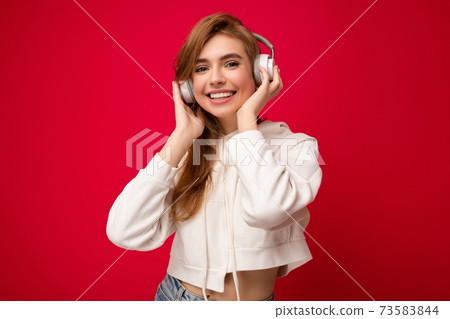 Photo of beautiful happy smiling young blonde woman wearing white hoodie isolated over colourful 73583844