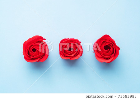 Handmade soap in the shape of a rose, red rose flower on a blue background. Top view, minimalist, copy space. Handmade soap in the shape of a rose, red rose flower on a blue background. Top view, minimalist, copy space. 73583983