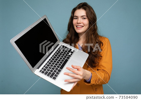 Photo of Beautiful smiling happy young woman holding computer laptop looking at camera having fun 73584090