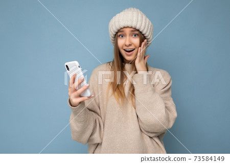 Photo of amazed positive beautiful young blonde woman wearing stylish beige warm sweater and knitted 73584149