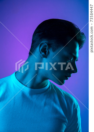 Handsome caucasian man's portrait isolated on purple studio background in neon light, monochrome Handsome caucasian man's portrait isolated on purple studio background in neon light, monochrome 73584447