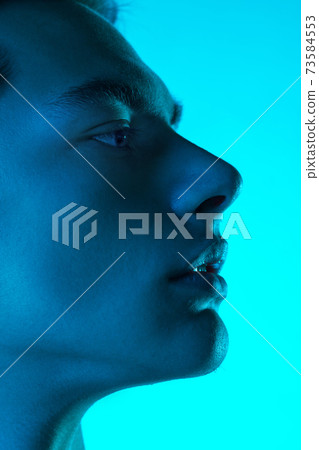 Handsome caucasian man's portrait isolated on blue studio background in neon light, monochrome Handsome caucasian man's portrait isolated on blue studio background in neon light, monochrome 73584553