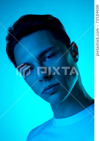 Handsome caucasian man's portrait isolated on blue studio background in neon light, monochrome 73584606