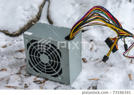 The PC power supply lies at an electronics dump in winter in the snow The PC power supply lies at an electronics dump in winter in the snow 73586391