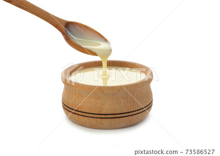 Spoon and bowl with condensed milk isolated on white background Spoon and bowl with condensed milk isolated on white background 73586527