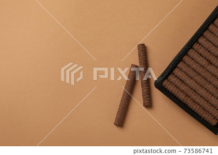 Plastic box with chocolate wafer rolls on brown background 73586741