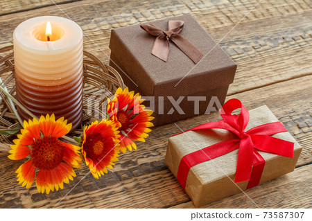 Gift boxes, candle and fresh flowers on wooden table. 73587307
