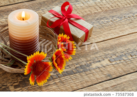 Gift box, candle and fresh flowers on wooden table. Gift box, candle and fresh flowers on wooden table. 73587308