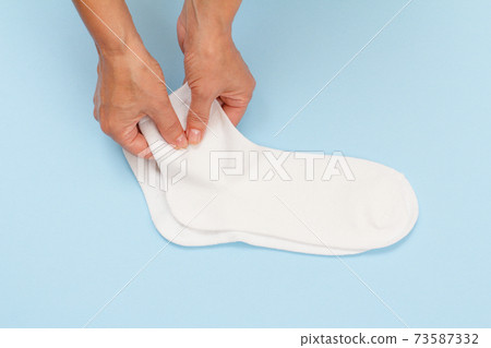 Female hands with pair of women socks on blue background. Female hands with pair of women socks on blue background. 73587332