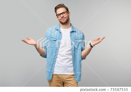 Portrait of confused clueless young man in jeans shirt standing over grey background Portrait of confused clueless young man in jeans shirt standing over grey background 73587533