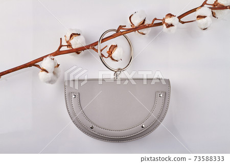 Small lilac purse is hanging on a cotton branch. Small lilac purse is hanging on a cotton branch. 73588333