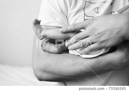 Father holds on arm of the newborn child 73588385