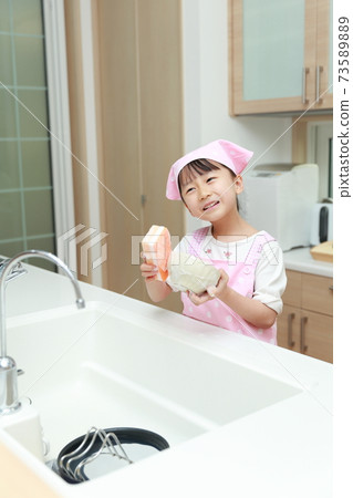 5-year-old girl helping to wash dishes 73589889