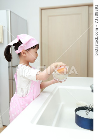 5-year-old girl helping to wash dishes 73589893