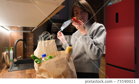Woman takes off mask to smell fresh vegetables in kitchen Woman takes off mask to smell fresh vegetables in kitchen 73590021
