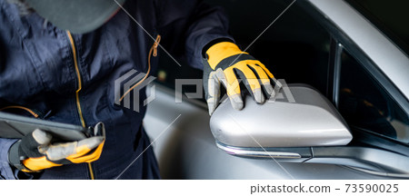 Asian auto mechanic checking car wing mirror Asian auto mechanic checking car wing mirror 73590025