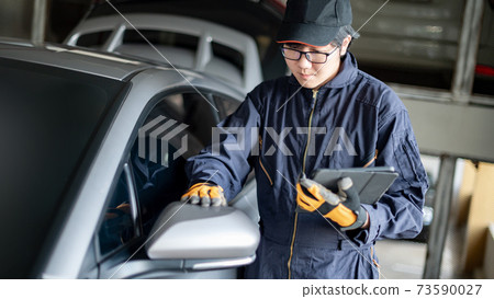 Asian auto mechanic checking car wing mirror Asian auto mechanic checking car wing mirror 73590027
