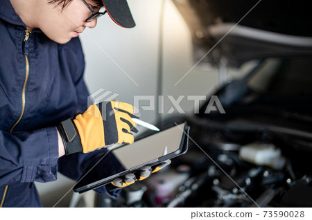 Asian auto mechanic checking the car using tablet Asian auto mechanic checking the car using tablet 73590028