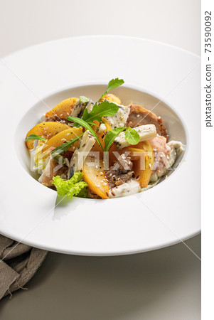Quick and healthy food recipes. Salad with vegetables, herbs, turkey sous vide meat, caramelized pear, blue cheese with sesame dressing on white plate. Mediterranean dish recipes. Close-up Quick and healthy food recipes. Salad with vegetables, herbs, turkey sous vide meat, caramelized pear, blue cheese with sesame dressing on white plate. Mediterranean dish recipes. Close-up 73590092