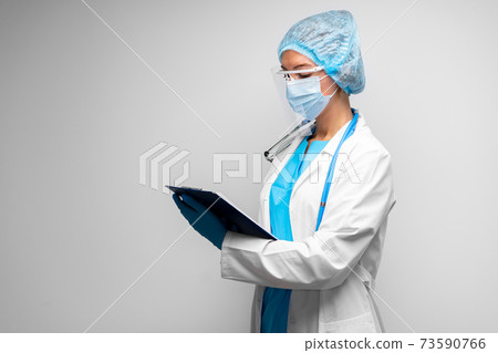 Woman doctor in medical mask standing with clipboard against gray background 73590766