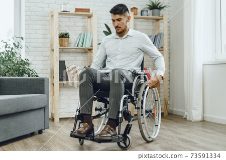 Portrait of disabled man in formal wear sitting in a wheelchair Portrait of disabled man in formal wear sitting in a wheelchair 73591334