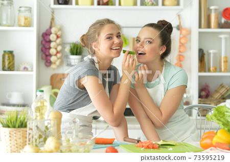 Portrait of beautiful teenagers cooking in kitchen Portrait of beautiful teenagers cooking in kitchen 73595219