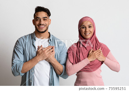 Grateful muslim couple keeping both hands on chest, expressing gratitude and appreciation Grateful muslim couple keeping both hands on chest, expressing gratitude and appreciation 73595251