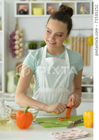 Beautiful young woman making salad at home Beautiful young woman making salad at home 73595252