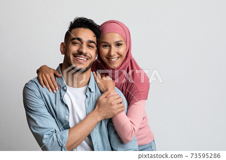Portrait of romantic smiling muslim couple posing over grey studio background Portrait of romantic smiling muslim couple posing over grey studio background 73595286