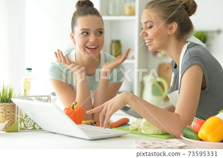 Portrait of beautiful teenagers making salad in kitchen 73595331