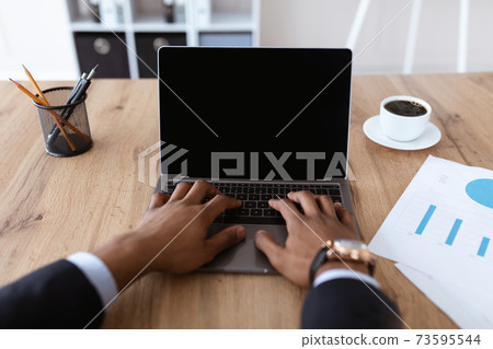 African american businessman hands typing on laptop with blank screen African american businessman hands typing on laptop with blank screen 73595544