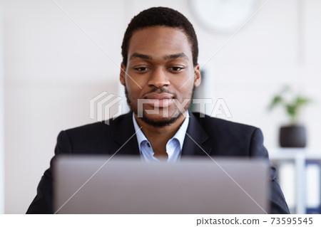 Closeup of handsome black businessman working with laptop Closeup of handsome black businessman working with laptop 73595545