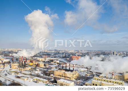 In the winter city, the factory's chimneys are smoking. The concept of air pollution. Environmental pollution by industrial waste 73596029