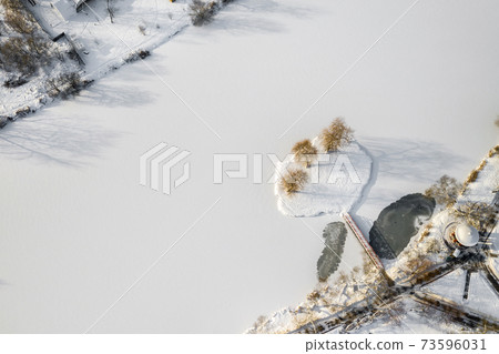 an island on a lake with a bridge in the Winter Loshitsky Park. Minsk, Belarus 73596031