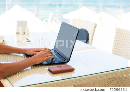 Workplace in a cafe with a sea view. Man working on a laptop in a cafe. Copy space. Mock up. Workplace in a cafe with a sea view. Man working on a laptop in a cafe. Copy space. Mock up. 73596284