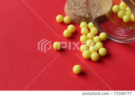 Homeopathy vitamins are scattered on a red background with a copyspace place for text. Homeopathy vitamins are scattered on a red background with a copyspace place for text. 73596777