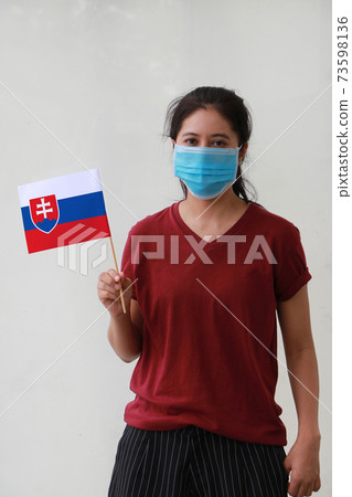 Masked woman in brown shirt and Slovakia flag in hand. Masked woman in brown shirt and Slovakia flag in hand. 73598136