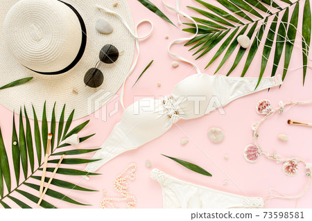 Traveler accessories, women summer bikini set swimsuit, tropical palm leaf branches on pink background. Travel vacation concept. Flat lay, top view. Traveler accessories, women summer bikini set swimsuit, tropical palm leaf branches on pink background. Travel vacation concept. Flat lay, top view. 73598581