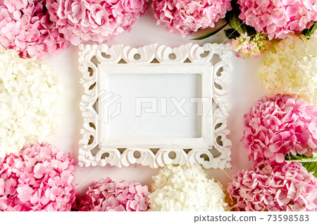 Carved, white frame decorated of pink hydrangea flowers on white background. Floral concept. Flat lay, top view.  73598583