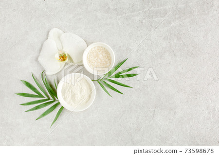 Spa treatment concept. Natural Organic spa cosmetics products, sea salt, and tropic palm leaves on gray marble table from above. Spa background  73598678
