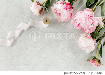Beautiful pink peony flowers on gray stone table with copy space for your text. Flat style, top view Beautiful pink peony flowers on gray stone table with copy space for your text. Flat style, top view 73598681