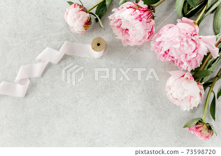 Beautiful pink peony flowers on gray stone table with copy space for your text. Flat style, top view 73598720